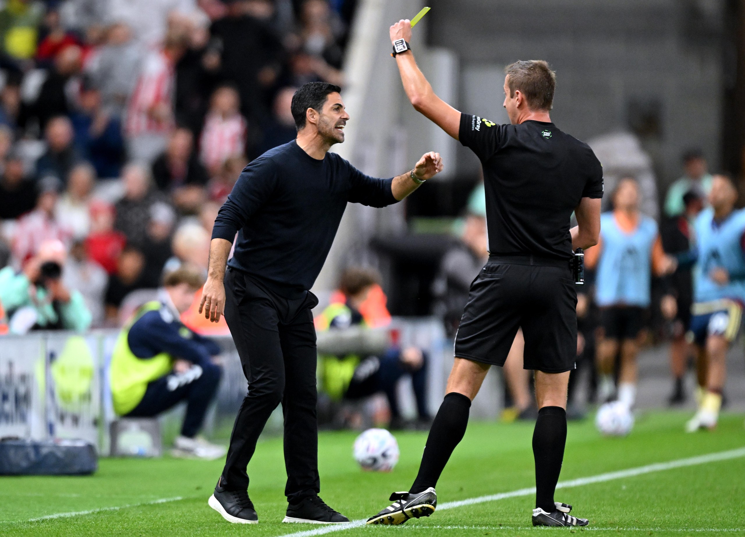 Mikel Arteta, Manager of Arsenal, receives a yellow card from referee John Brooks.